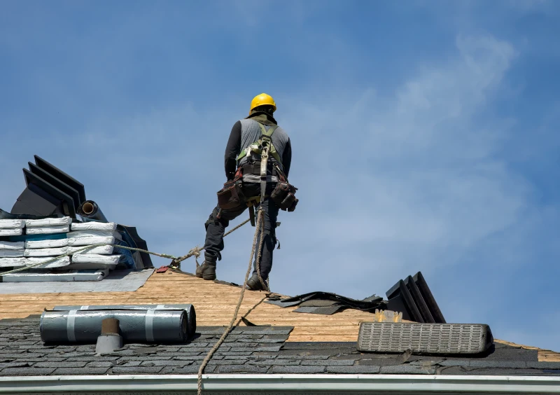 Worker on roof with safety gear.